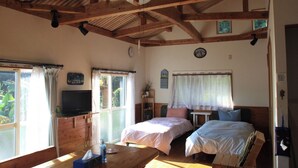 A room with two beds, a wooden ceiling, a television, and a table with a bottle. - Diving & Pension Riki (Setouchi)