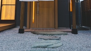 A wooden door with a metal handle, flanked by two wooden posts, leading to a tiled entrance area. - Vacation Rental Hitoritoiro (Annaka)