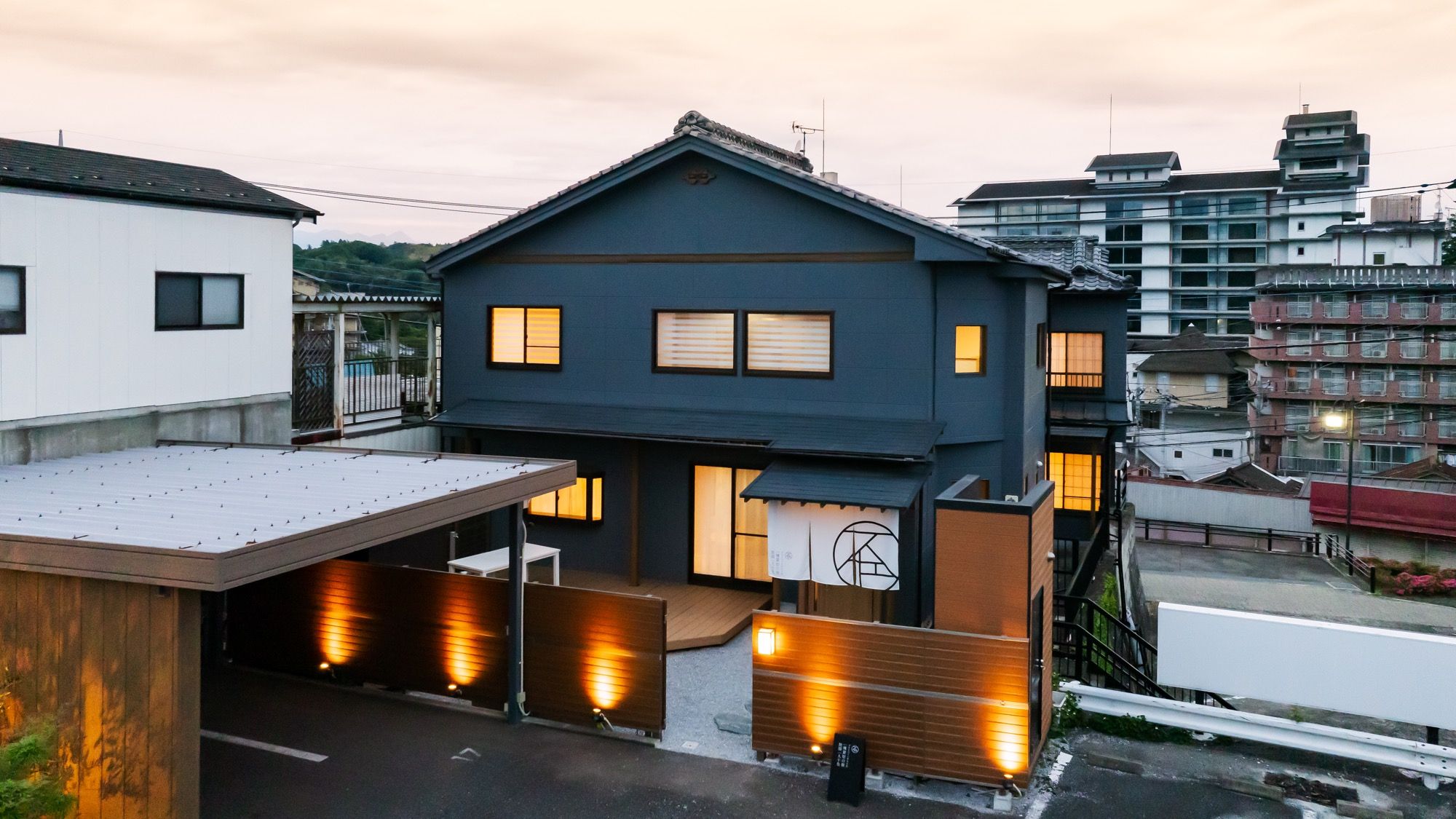 Un edificio residencial moderno de dos pisos con techo plano y zona de garaje cubierta.