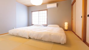 A bedroom with tatami flooring, a large window, a bed with white bedding, and a bedside lamp. - Vacation Rental Hitoritoiro (Annaka)