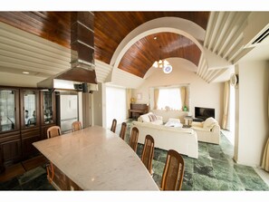 A spacious living area with a large dining table, comfortable seating, and a cozy fireplace. - Seaside Tellme <ishigakijima> (Ishigaki)