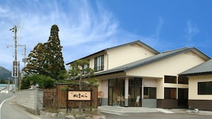 A building with a sign that reads '新たまら' and a large tree in front.