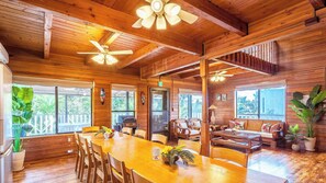 Un intérieur spacieux en bois, comprenant un coin repas, des sièges et un ventilateur de plafond.