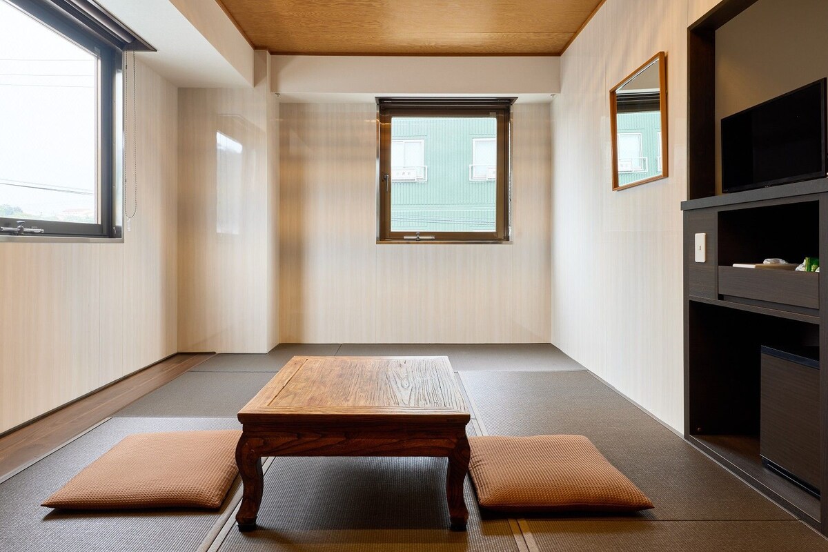 A minimalist room with tatami flooring, a wooden table, and a built-in TV shelf.