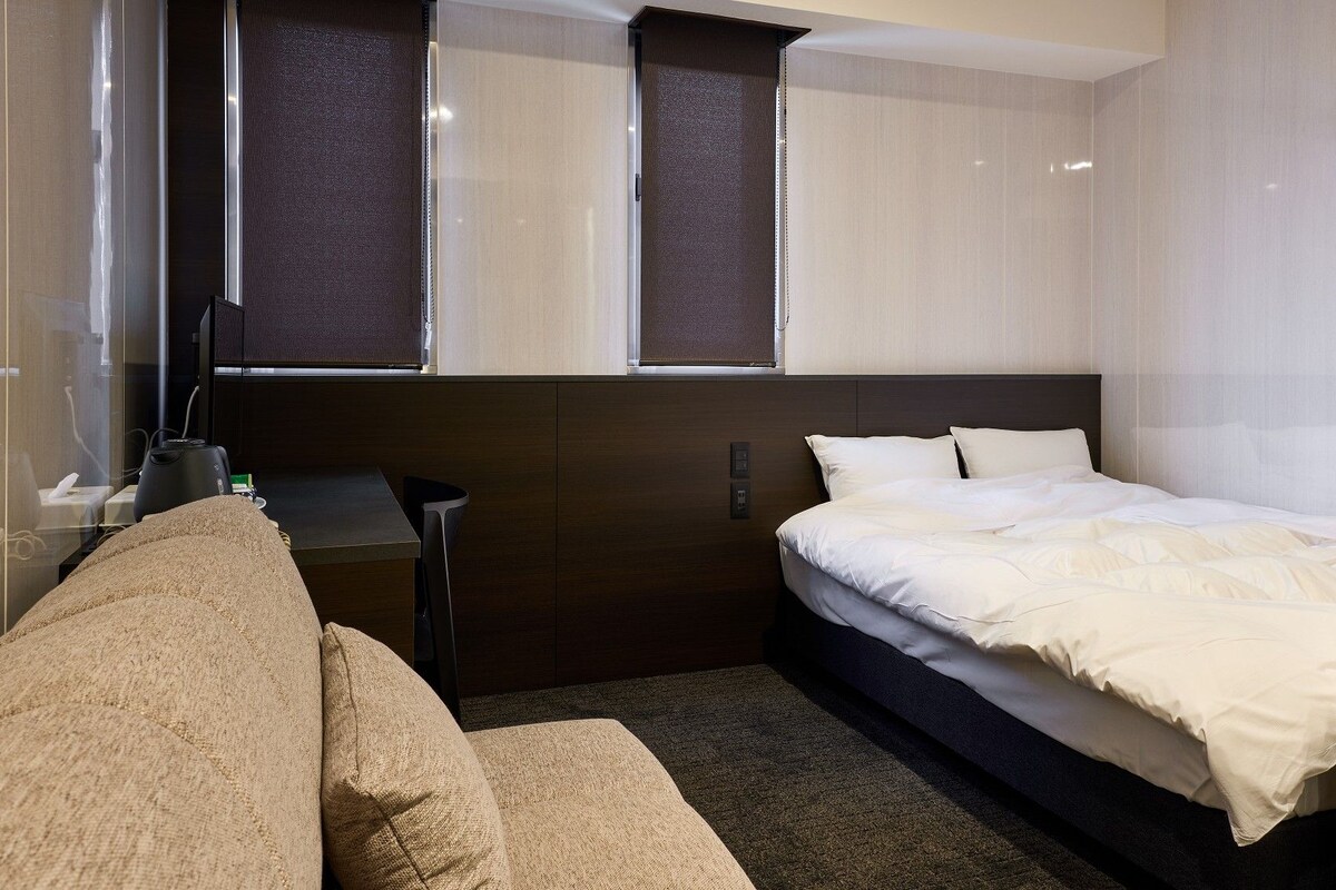 A hotel room with a bed, a desk, and a chair.