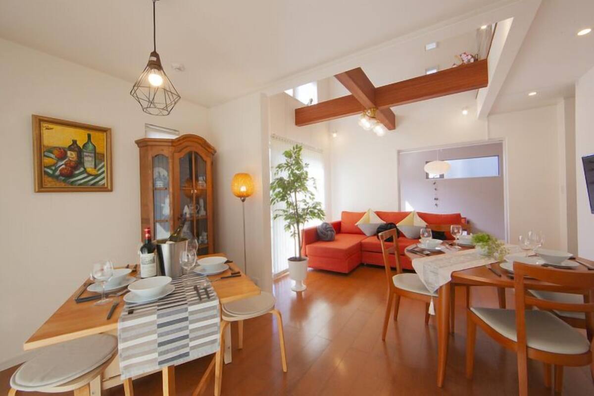 A dining area with a wooden table set for four, a red sofa, and a wooden cabinet with glass doors.