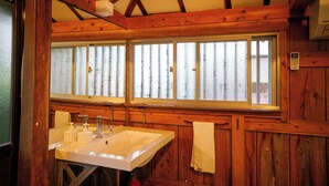 A wooden cabin bathroom with a large window, a sink, and a towel hanging on the wall. - Denpaku Beach View Roof (Setouchi)