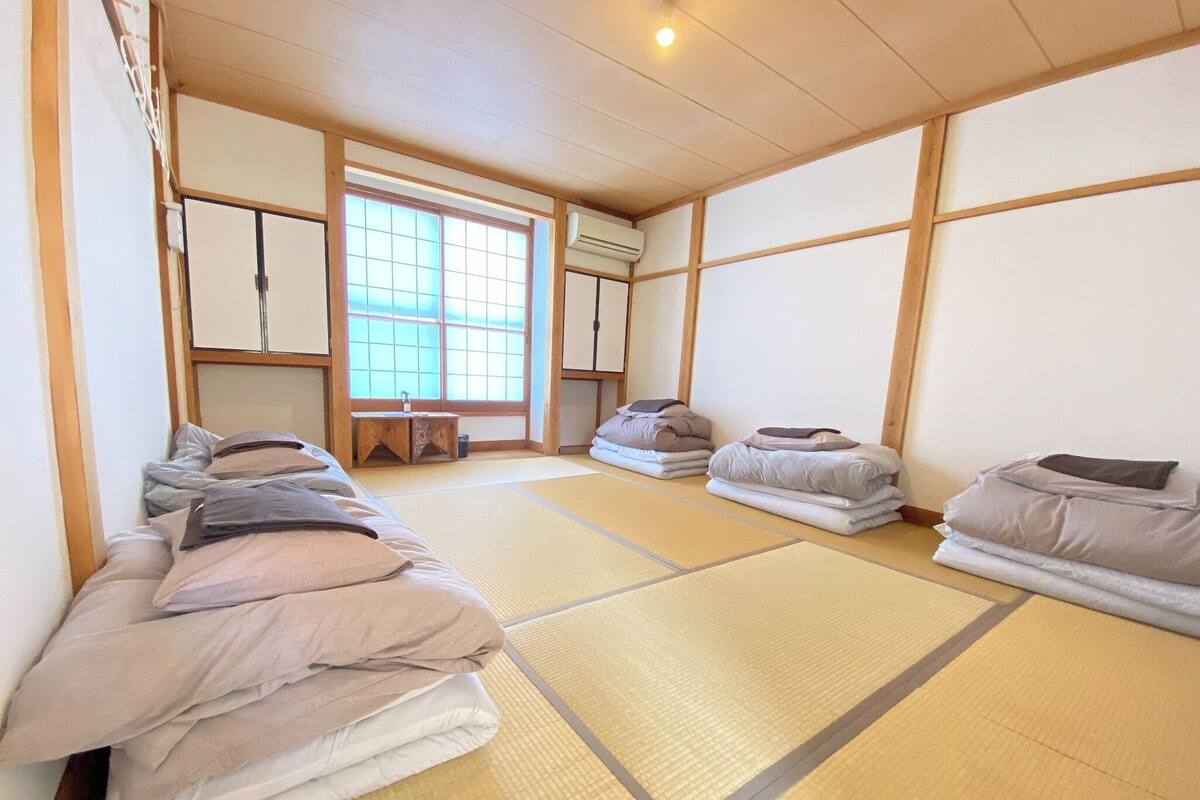 Een traditionele Japanse kamer met tatami vloeren, futonbedden, een shoji scherm en een kleine houten tafel.