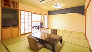 Ett traditionellt japanskt rum med tatamimattor på golvet, ett lågt bord och en tv-apparat placerad på ett skåp.