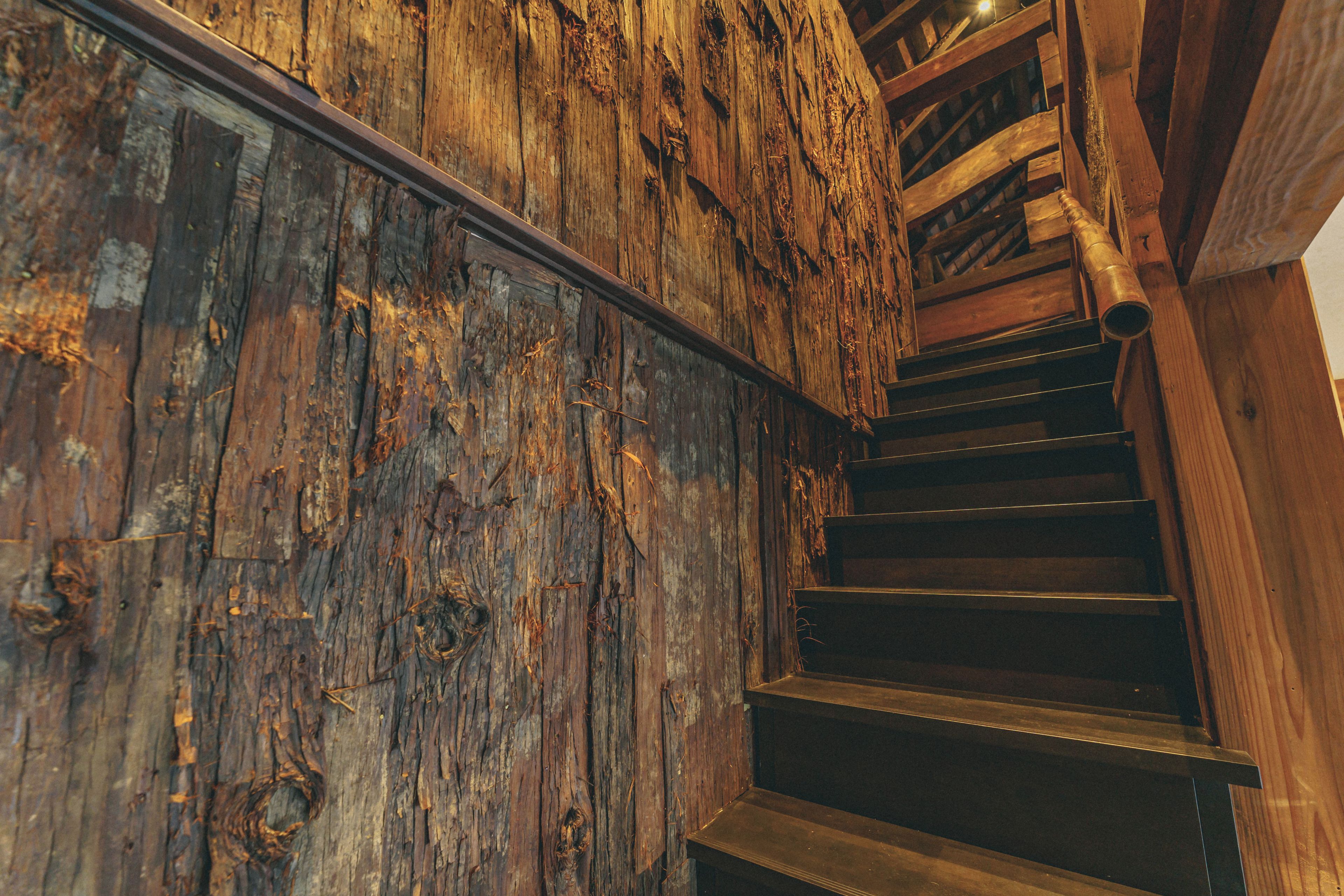 Una escalera de madera con diseño rústico, que incluye un muro de madera y un barandal de metal.