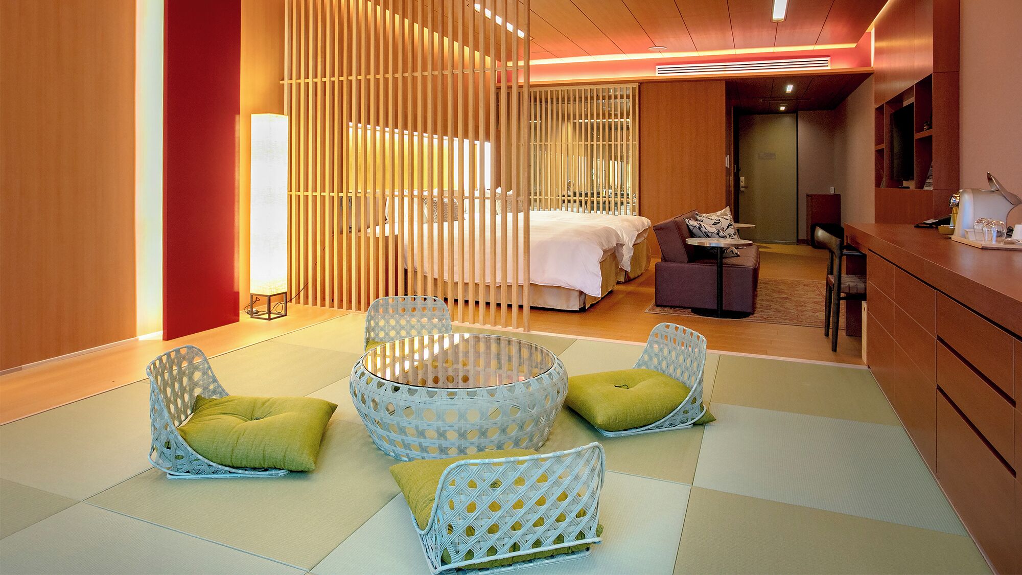 A hotel room with a bed, a sitting area with chairs, a small table, and a desk with a computer.