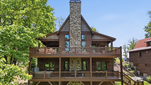 A two-story wooden cabin with a stone chimney, balconies, and a deck. - Birch and Squirrel - Quiet Luxury, Near Great Camp & Downtown Banner Elk (Banner Elk)