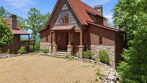 A two-story wooden house with a stone foundation, a red roof, and a gravel driveway. - Birch and Squirrel - Quiet Luxury, Near Great Camp & Downtown Banner Elk (Banner Elk)