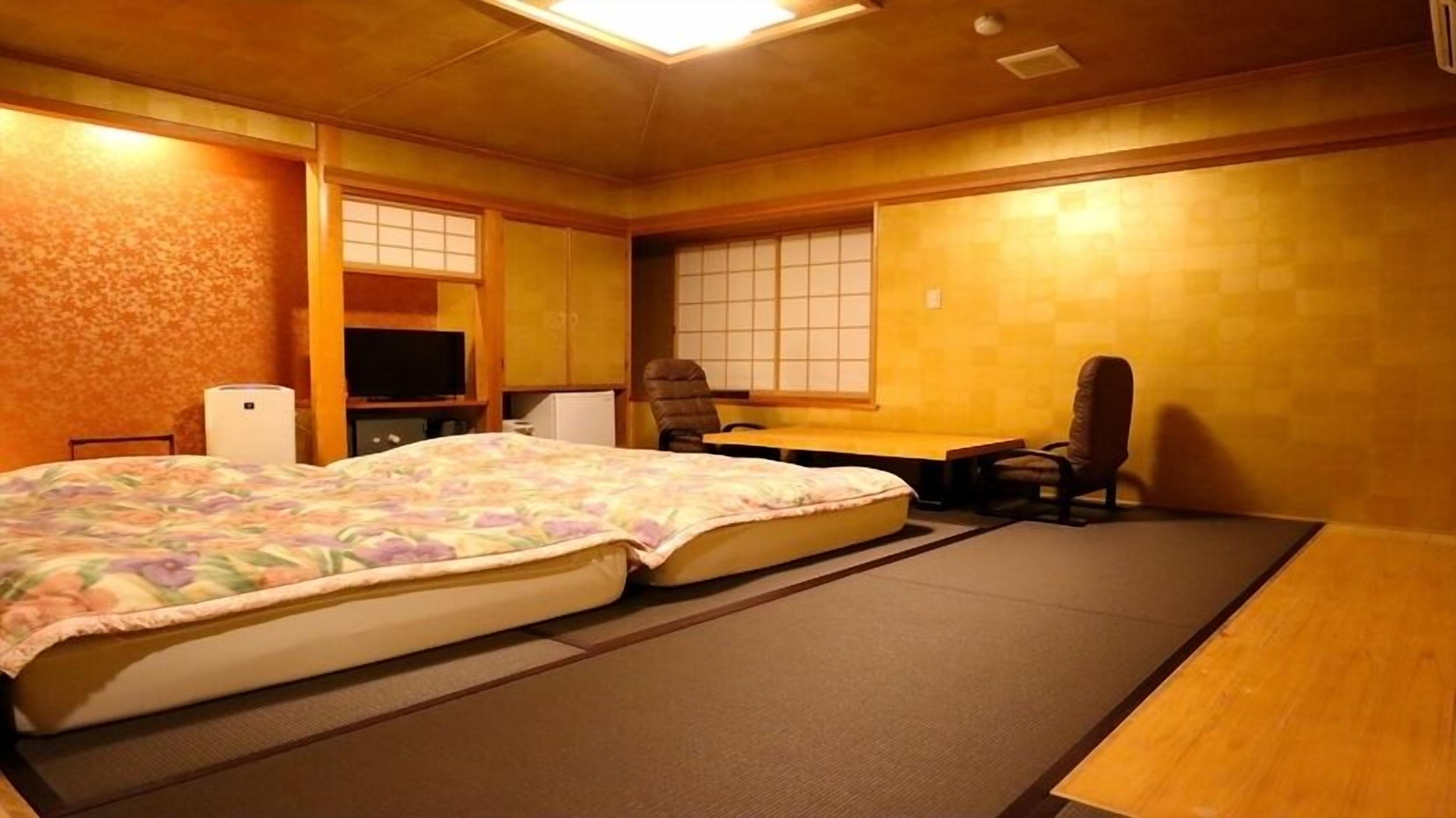 Habitació d'estil japonès tradicional amb tatami, un llit futó, una taula i una cadira.