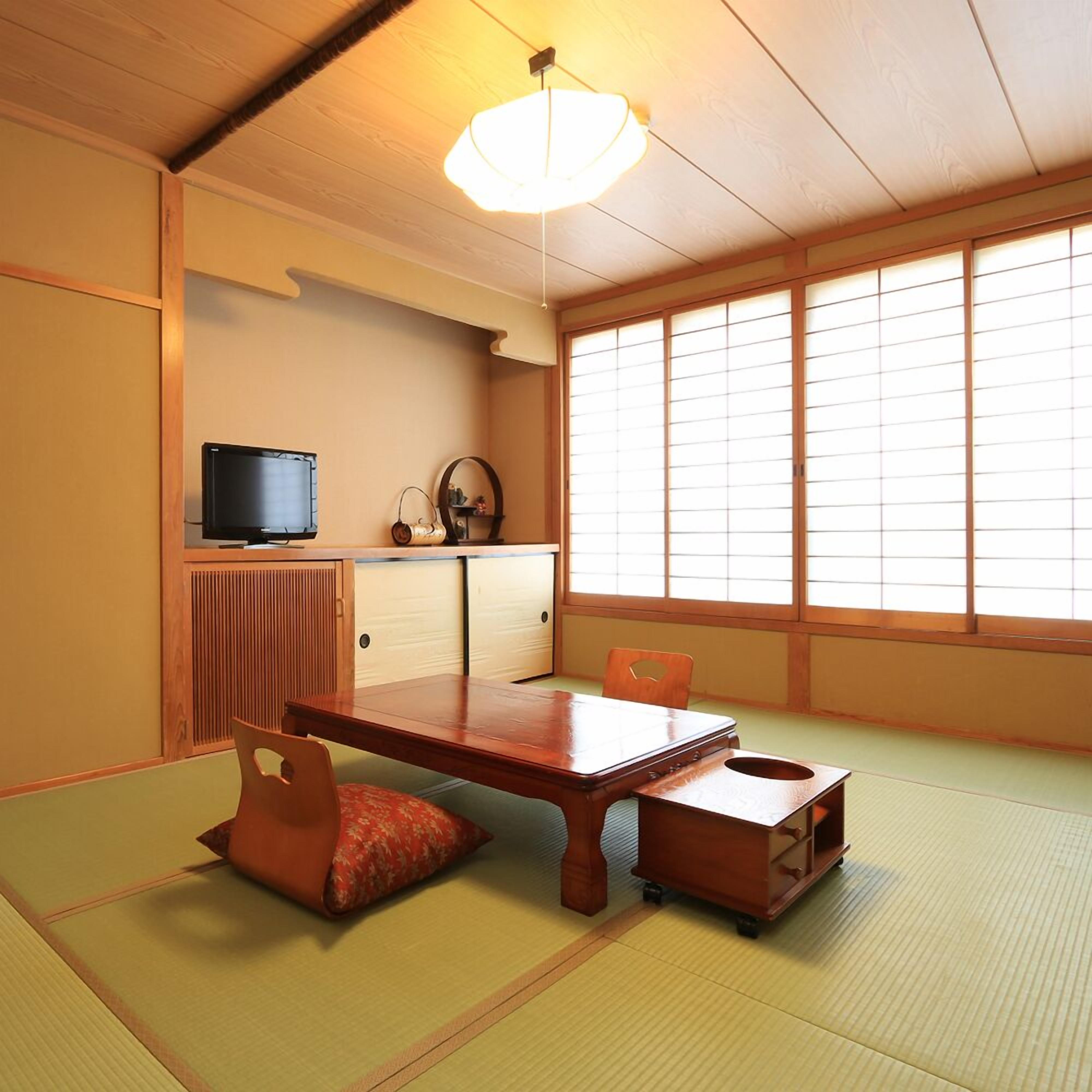 Une pièce de style japonais traditionnel, avec un sol recouvert de tatamis, une table basse, un téléviseur et des portes coulissantes.