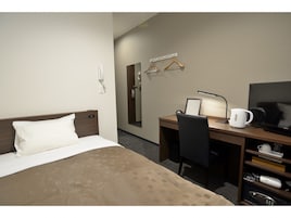 Una camera d'albergo con un letto, una scrivania, una sedia, una televisione e una macchina del caffè.