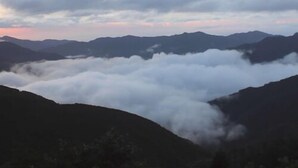 A mountainous landscape with a valley of clouds.