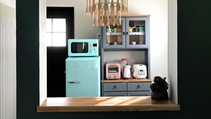 Uma cozinha com micro-ondas, torradeira, máquina de café e um armário com utensílios.
