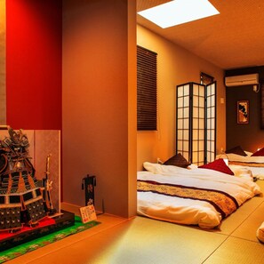 A traditional Japanese-style room with tatami flooring, shoji screens, and a futon bed arrangement.