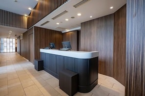 Una reception dalla forma curva, affiancata da pannelli in legno e un pavimento piastrellato.