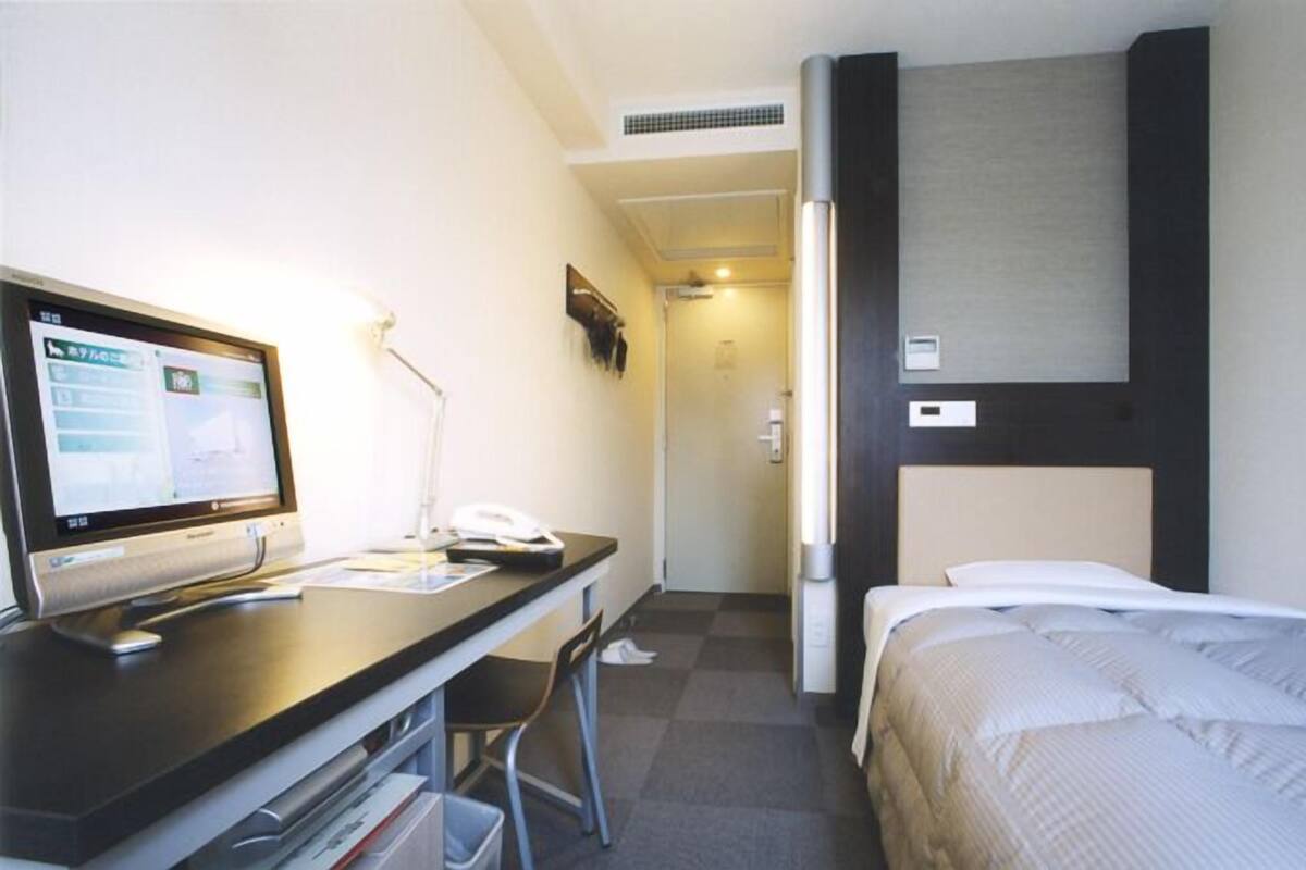 Habitación de hotel con escritorio, silla, cama y televisión.