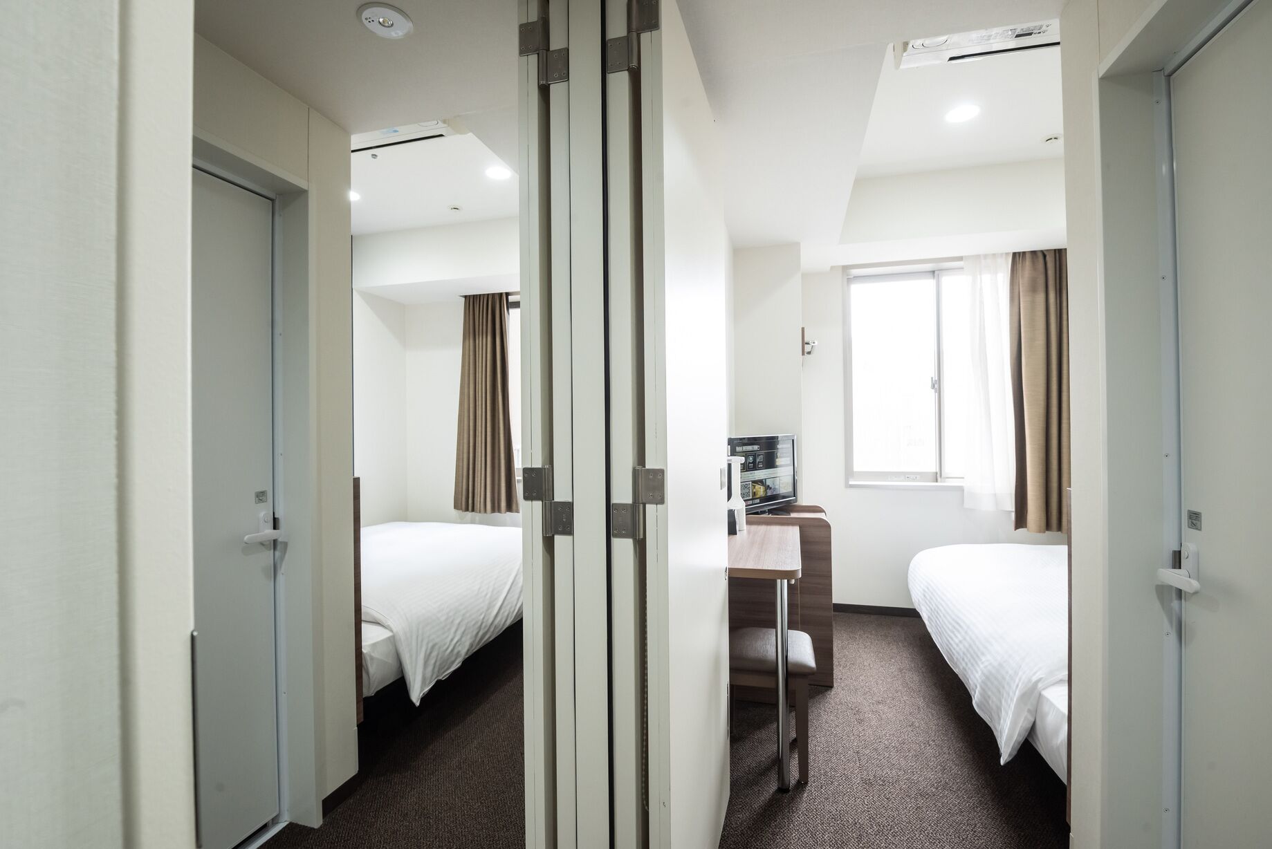 Ett hotellrum med två sängar, ett skrivbord, ett fönster och en minibar.