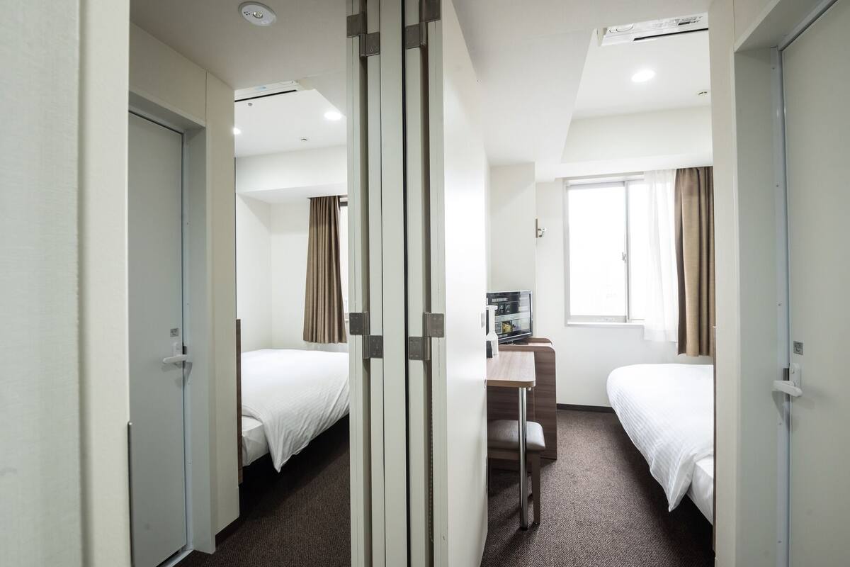 Habitación de hotel con dos camas, un escritorio, una ventana y un mini bar.