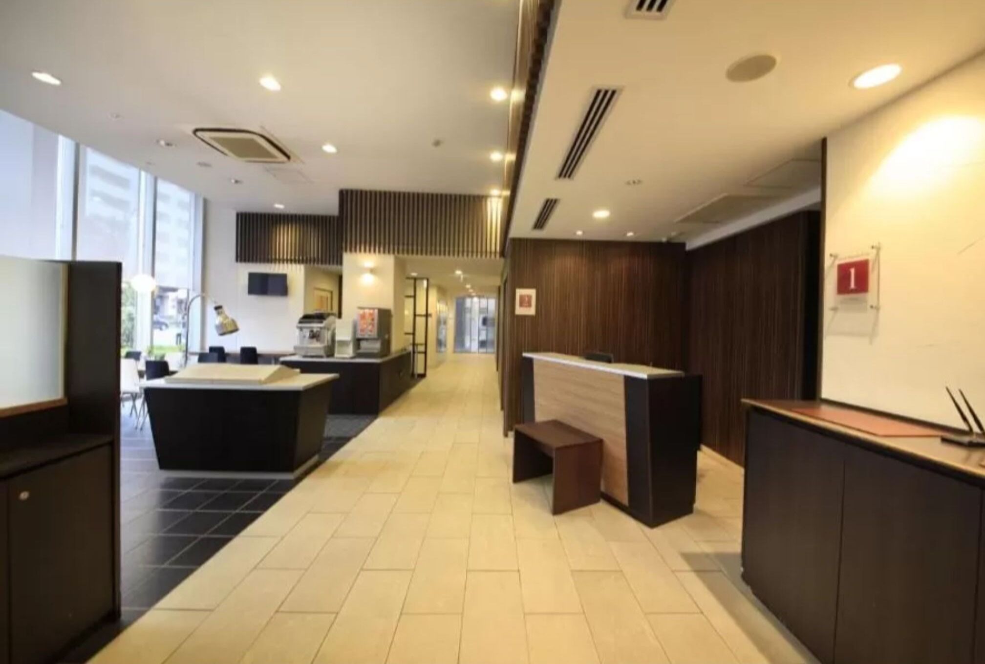 En modern hotellobby med en receptionsdisk, en sittgrupp och en vy över lobbyn i bakgrunden.