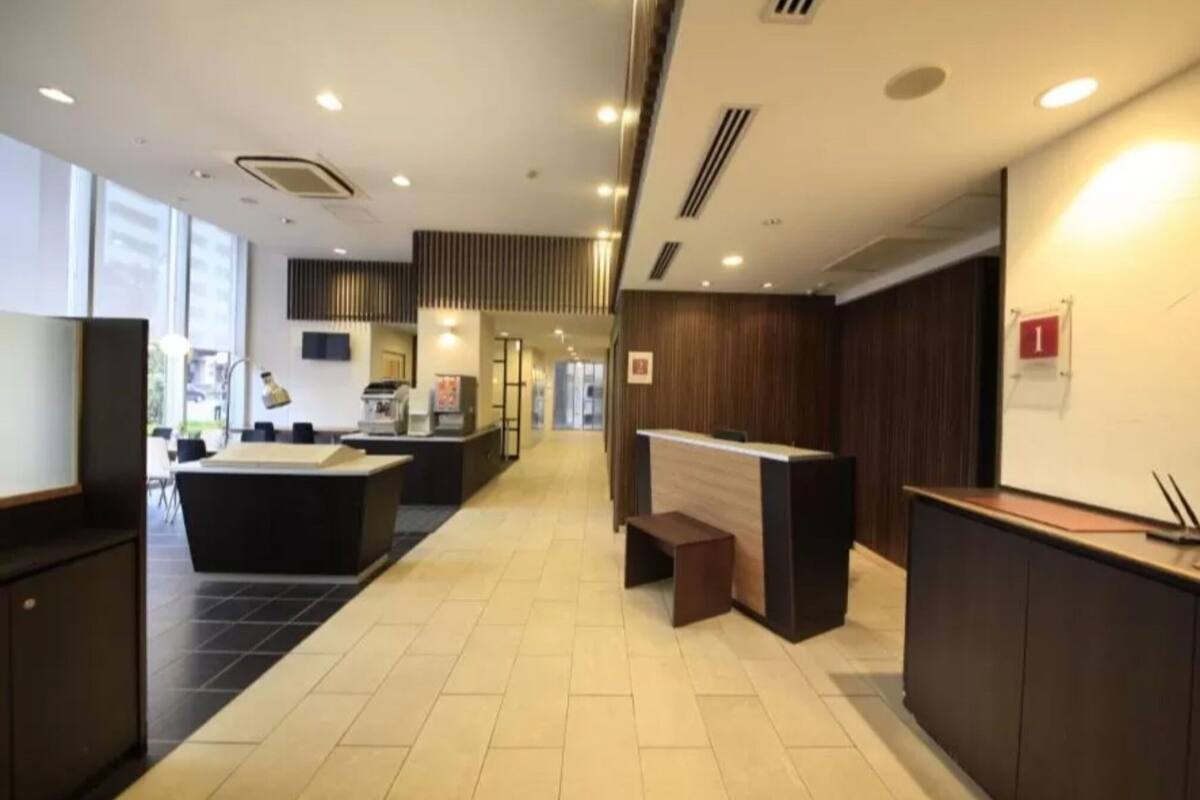 Un moderno vestíbulo de hotel con mostrador de recepción, zona de estar y amplios ventanales.