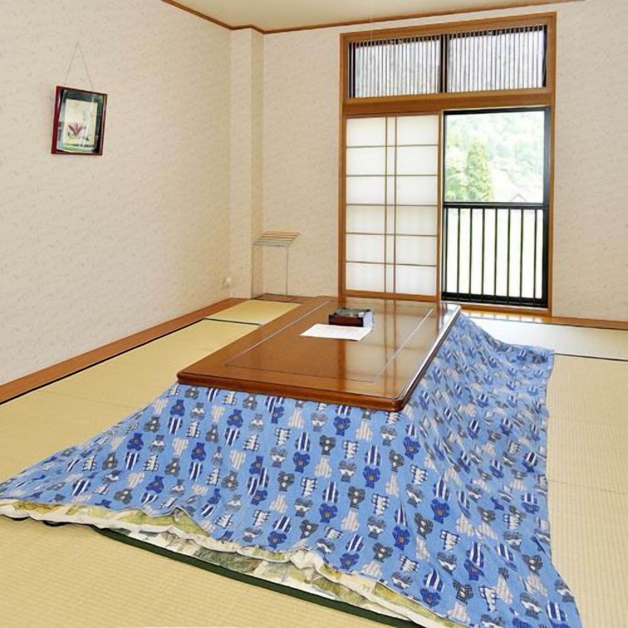A tatami mat room with a low table, a window with a view, and a framed picture on the wall.