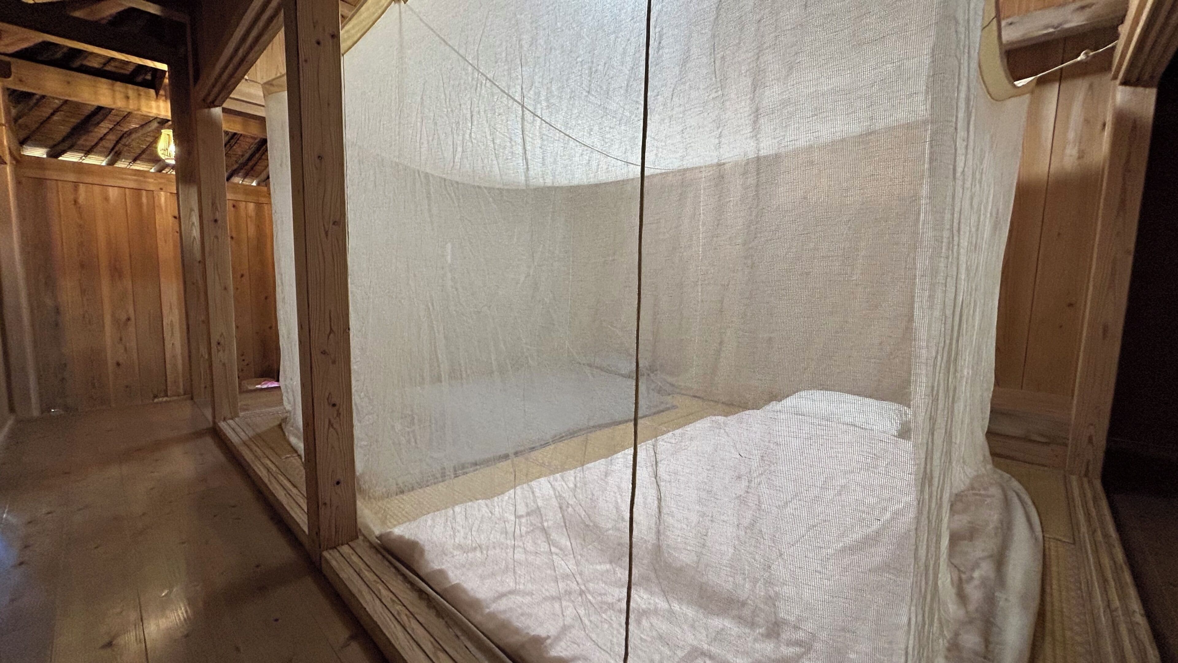 A wooden room with a bed and a mosquito net.