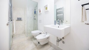 Ein modernes Badezimmer mit einer Duschkabine aus Glas, einem weißen Waschbecken und einem Bidet.