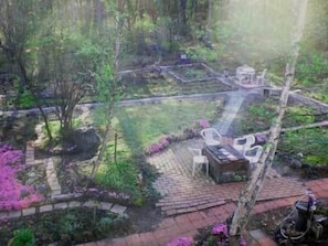 A garden with a brick pathway, a wooden bench, and a table with chairs.