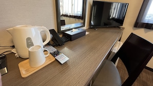 A hotel room with a wooden desk, a white coffee maker, a remote control, a black telephone, and a television. - Hana Hotel Isesaki (Isesaki)