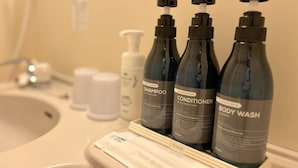A bathroom counter with toiletries including shampoo, conditioner, body wash, and a toothbrush. - Hana Hotel Isesaki (Isesaki)