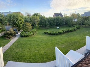 Ein Wohnhausgarten mit Rasenfläche, einem Weg und einer Bank.