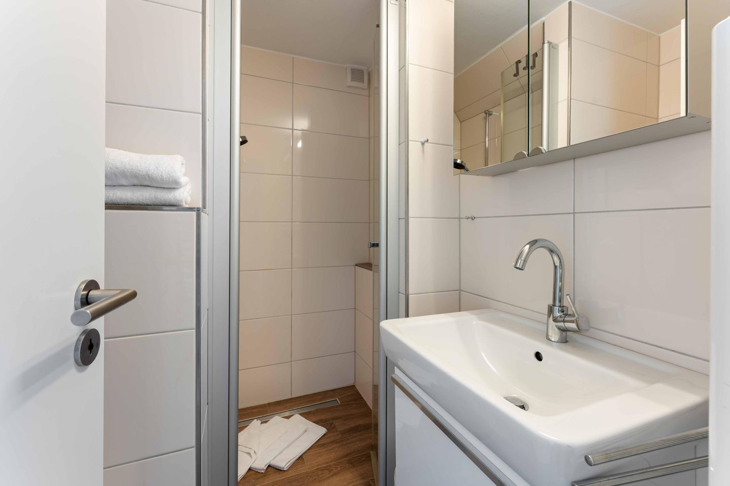 A bathroom with a white sink, a mirror, and a shower area.
