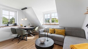 Um apartamento loft moderno com área de jantar, um sofá cinza com almofadas amarelas e uma mesa de centro redonda.
