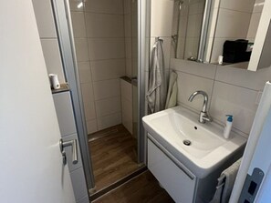 Ein Badezimmer mit Dusche, Waschbecken und Spiegel.