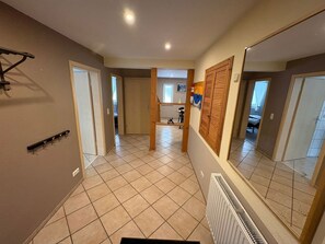 Un couloir avec un radiateur, un porte-manteau et un mur recouvert de miroirs.