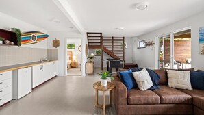 A modern kitchen with white cabinets, a wooden countertop, and a colorful decorative piece above the sink. - The Surf Nook | Walk to Beach | Family Friendly (Gracetown)