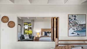 A bedroom with a bed, a nightstand, a lamp, a window, and a painting. - The Surf Nook | Walk to Beach | Family Friendly (Gracetown)