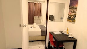 Ein Hotelzimmer mit einem Bett, einem kleinen Tisch mit Stuhl, einem Spiegel und einem Bild an der Wand.