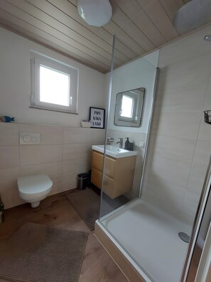 Un baño moderno con inodoro, lavamanos y ducha.