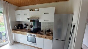 Een moderne keuken met witte kasten, een roestvrijstalen koelkast, een inbouwoven en een gasfornuis.