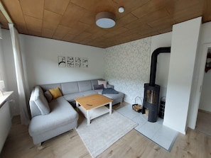 Una sala de estar moderna con un sofá gris, una mesa de centro de madera y un estufa de leña negra.