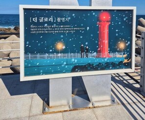 A signboard with a lighthouse and text, placed on a metal stand. - Nova Stay Gangneung (Gangneung)