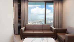 A modern living room with a sofa and a marble coffee table, large windows with curtains, and a city view. - Nova Stay Gangneung (Gangneung)