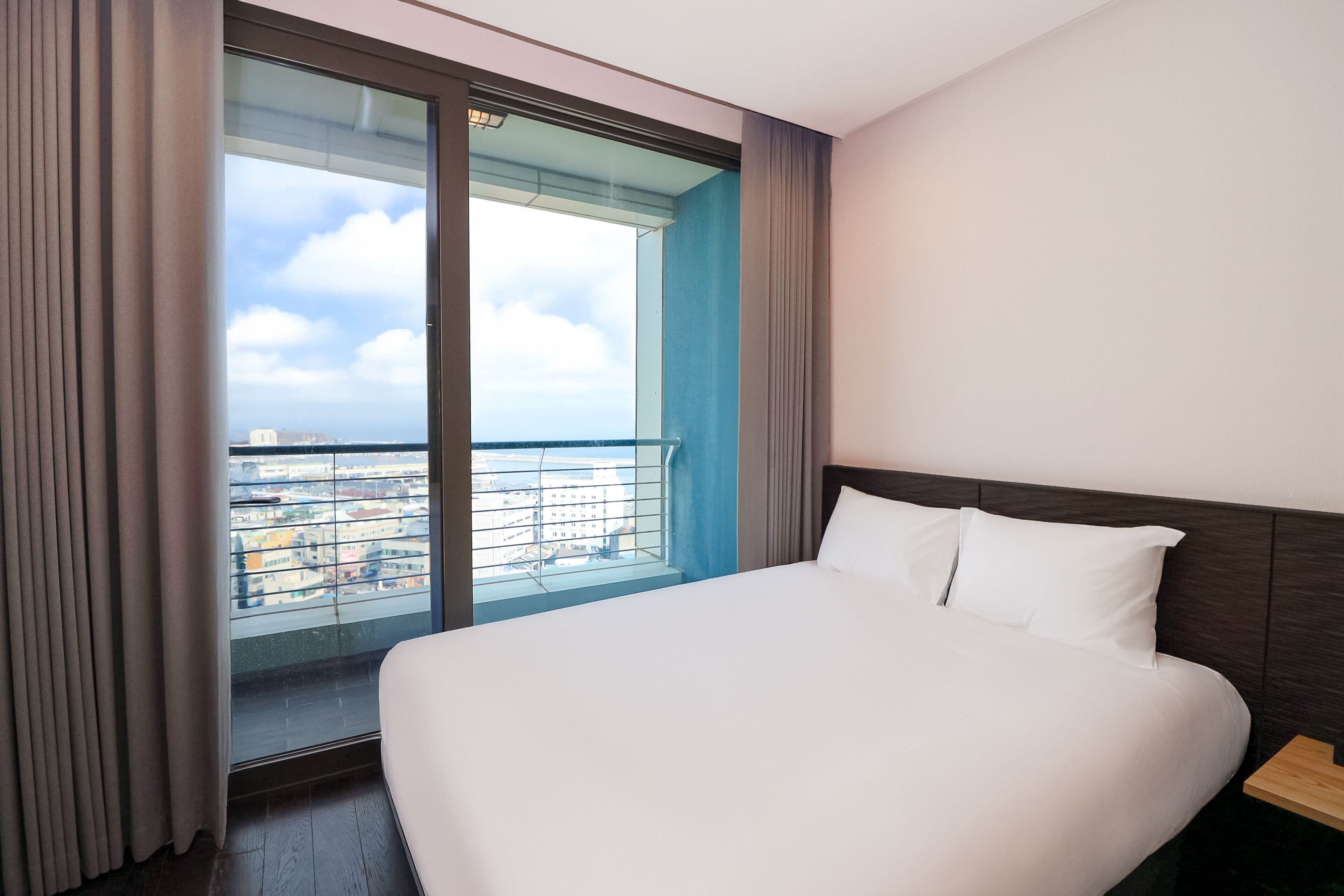 Et hotelværelse med en stor seng, udsigt over byen fra en balkon, og et moderne design.