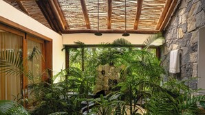 A room with a stone wall, a wooden door, and a thatched roof. - Avana Holiday Experiences (Kalpetta)